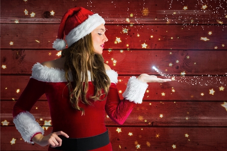 Beautiful woman in santa costume blowing a kiss against wooden backgroundの写真素材