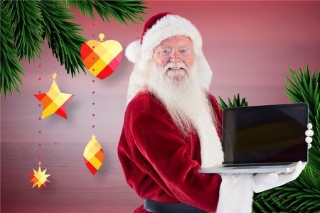 Portrait of santa claus holding a laptop during christmas timeの写真素材