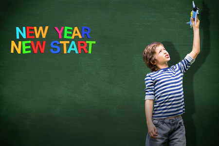 Child holding airplane against green chalkboardの写真素材