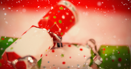 Snow falling against close-up of christmas crackers on snowの写真素材