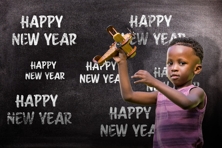 Child holding wooden airplane against black backgroundの写真素材