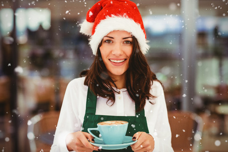 Portrait of woman with santa hat holding coffee against snow fallingの写真素材