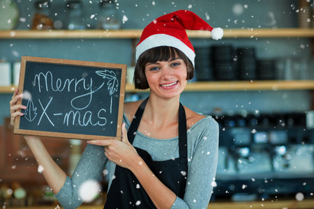 Portrait of waitress showing slate with merry x-mas text against snow fallingの写真素材