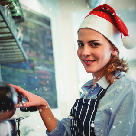 Portrait of waitress using coffee maker at cafeteria during Christmas against snow fallingの写真素材