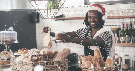 Smiling hipster employee serving take away products against snow fallingの写真素材