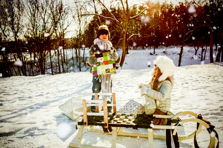 Brother and sister taking presents against snow falling