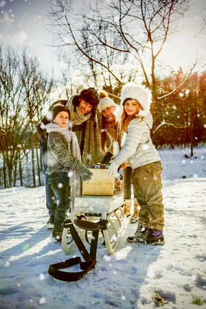Portrait of happy family holding presents  against snow fallingの写真素材