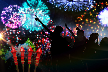 Silhouette children pointing against colourful fireworks exploding on black backgroundの写真素材