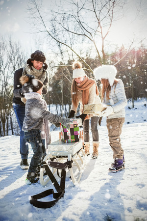 Happy family holding presents  against snow fallingの写真素材
