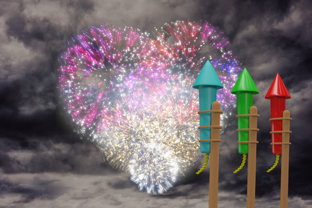 Rockets for fireworks against colourful fireworks exploding on black backgroundの写真素材