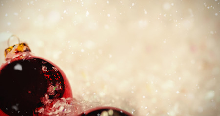 Snow falling against closeup of christmas baubles on snowの写真素材