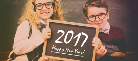 School kids holding chalkboard with new year text against blackboard