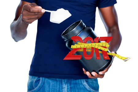 Mid section of man holding a scoop of protein mix against digitally generated image of new year with...