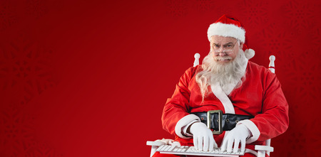 Santa Claus typing on keyboard  against red snowflake backgroundの写真素材