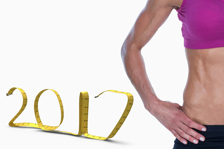 Female bodybuilder posing with hands on hips mid section against white background with vignette