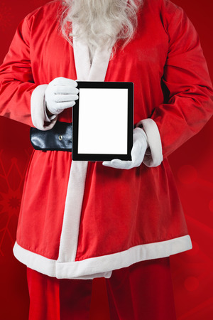 Midsection of Santa Claus showing digital tablet against red snowflake backgroundの写真素材