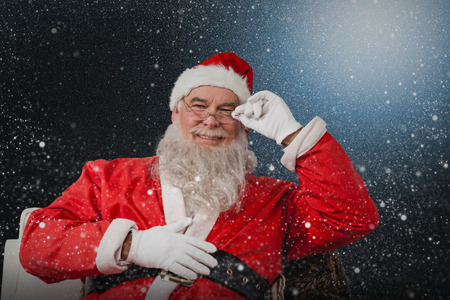 Smiling Santa Claus sitting on chair against snowflake patternの写真素材