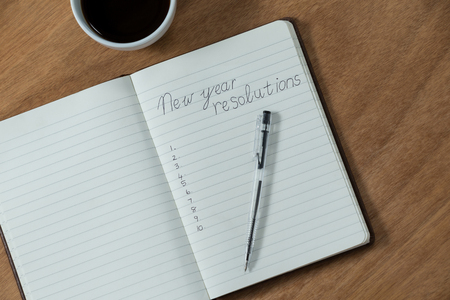 New year resolutions written on diary with coffee mug on wooden tableの写真素材