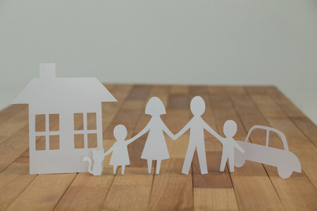 Paper cutout family with house and car on wooden plankの写真素材