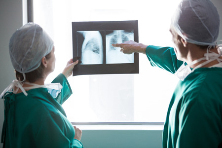 Surgeons examining an x-ray report in corridor of hospital