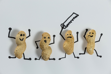 Four peanuts figurine having fun with saw on white backgroundの写真素材