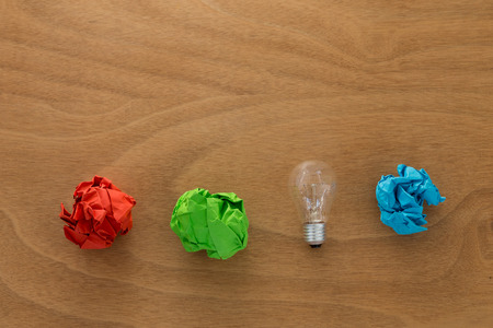 Great idea concept with crumpled colorful paper and light bulb on wooden tableの写真素材