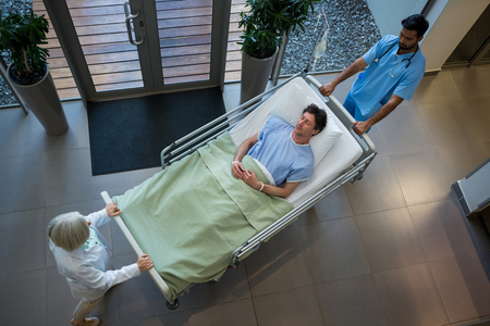 Doctors pushing emergency stretcher bed in corridor at hospitalの写真素材