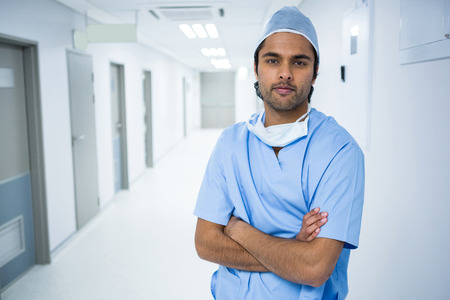 Portrait of surgeon standing with arms crossed in corridor of hospital