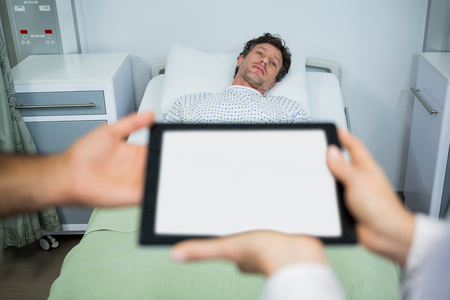 Doctors using digital tablet in ward while consulting patientの写真素材