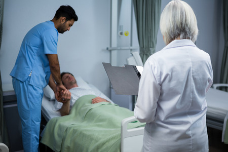 Doctor and surgeon consulting patient in ward of hospitalの写真素材
