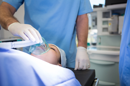 Doctor placing an oxygen mask on the face of a patient in hospitalの写真素材