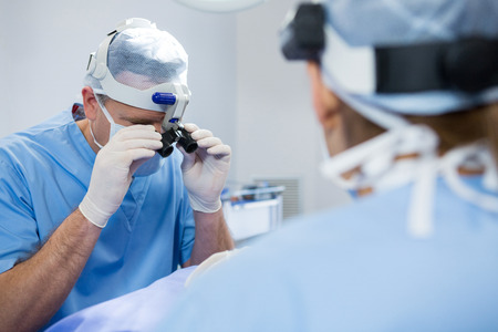 Surgeons wearing surgical loupes while operating patient in operation theaterの写真素材
