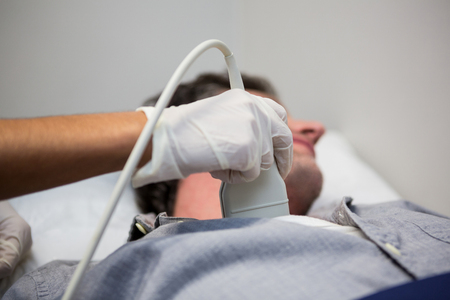 Doctors performing a doppler sonography on patient in hospitalの写真素材