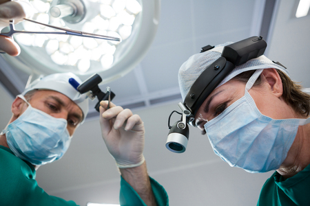 Surgeons holding surgical tool while operating in operation theaterの写真素材