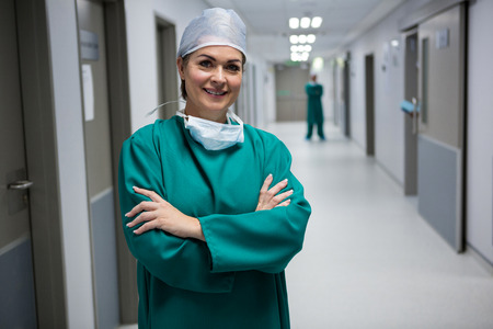 Portrait of female surgeon standing with arms crossed in corridor of hospitalの写真素材