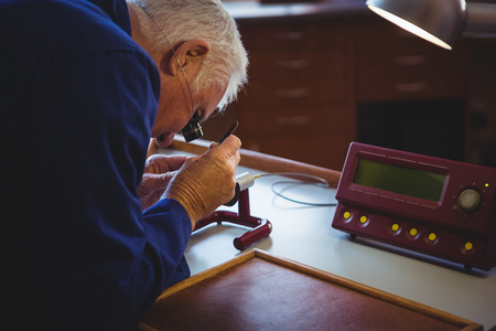 Horologist repairing a watch in the workshopの写真素材