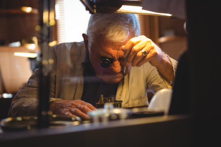 Horologist repairing a watch in the workshopの写真素材