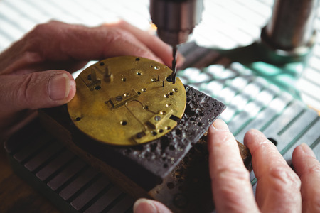Horologist drilling a dial plate in the workshop