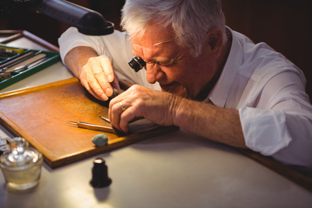 Horologist repairing a watch in the workshopの写真素材