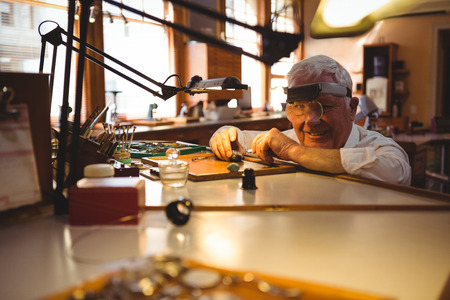 Portrait of horologist repairing a watch in the workshopの写真素材