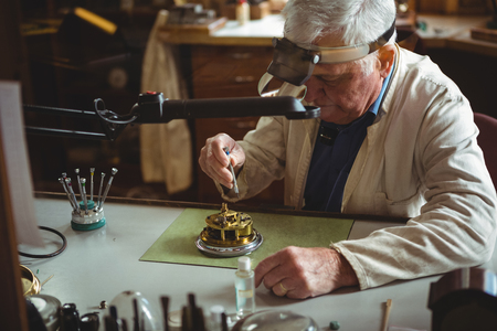 Horologist repairing a watch in the workshopの写真素材