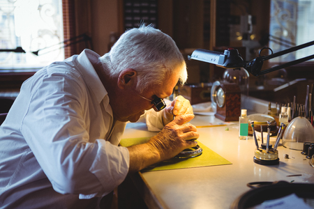 Horologist repairing a watch in the workshopの写真素材