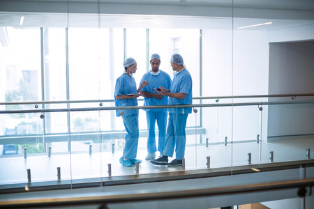 Team of surgeons discussing over digital tablet in hospital corridorの写真素材