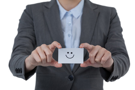 Businesswoman holding visitor card with smiley against white backgroundの写真素材