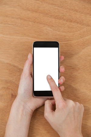 Close-up of hands using mobile phone against wooden backgroundの写真素材