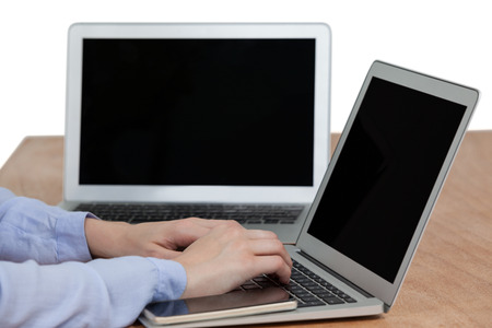 Businesswoman sitting at desk and using laptop against white background