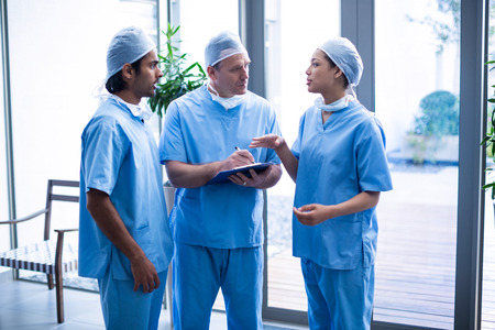 Team of surgeons discussing over medical reports in hospital corridorの写真素材