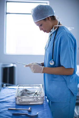 Female surgeon holding surgical equipment at hospitalの写真素材