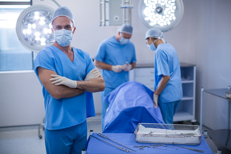 Portrait of surgeon standing with arms crossed in operation room at the hospital