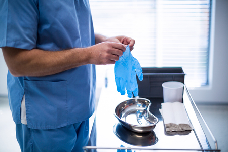 Mid section of surgeon wearing surgical glove at hospitalの写真素材